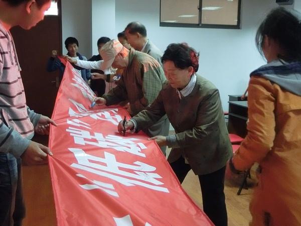 在“树立‘低碳’观念，创建绿色家园”横幅上签字（一）