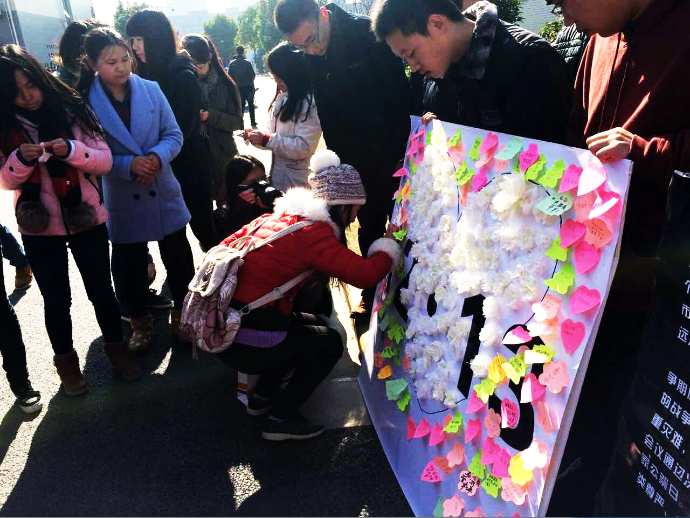 同学在展板上贴小白花，为逝者祈福