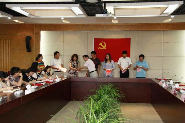 机关党委书记黄城芳向每位新党员颁发党章和党建书刊