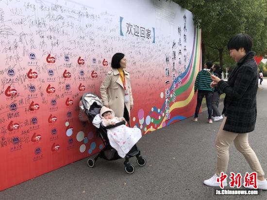 带着孩子在签名墙下合影的年轻校友。